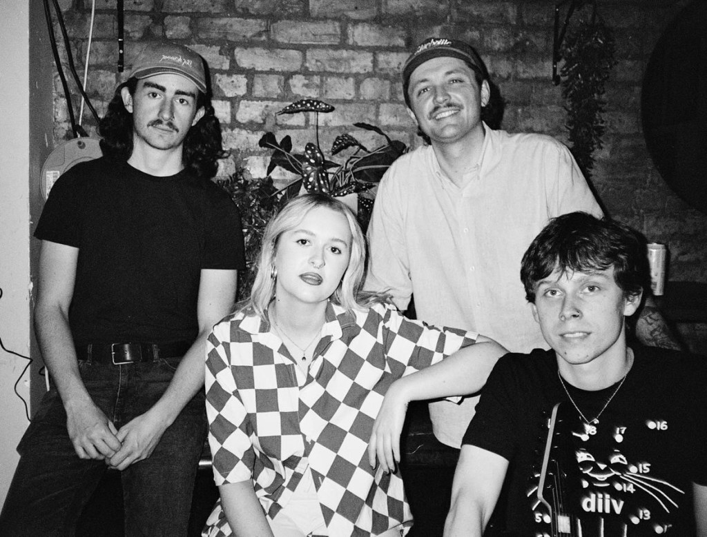 Four band members in black and white